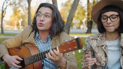 Portrait of Creative Youth Singing Playing the Guitar Relaxing in Urban Park