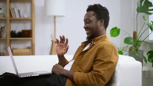 Man Waving During Video Call on Laptop