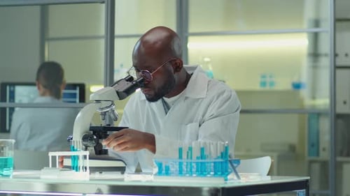 Scientist Analyzing Samples Under Microscope in Lab