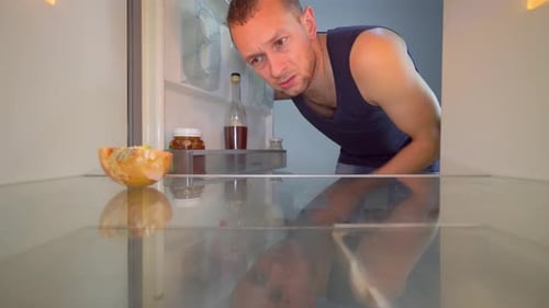 Man Inspecting Food Inside Empty Refrigerator