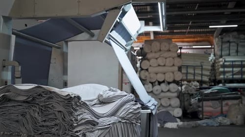 Industrial Machine is Laying Blue Woven Fabric, Folding Clothes Automatically in Factory in slowmo