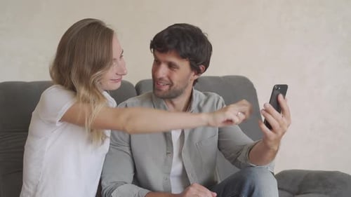 Couple Looking at Phone Together on Couch
