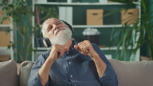 Senior Man Enjoys Music With Headphones at Home