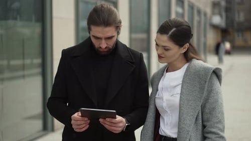Man and Woman Discuss Tablet Information Outside