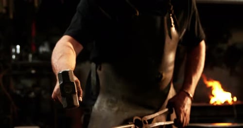 Blacksmith Shaping Hot Metal in Dark Workshop