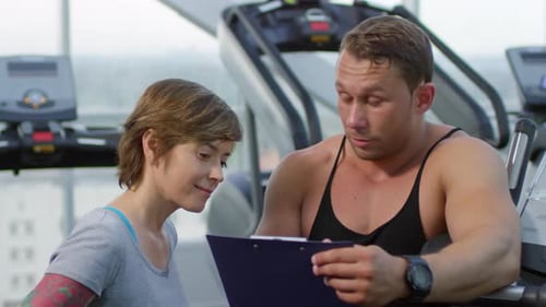 Fitness Trainer Talking to Woman in Gym