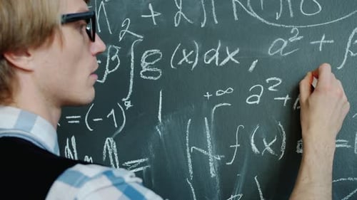 Young Mathematician Writing Formulas on Chalkboard Working with Serious Face