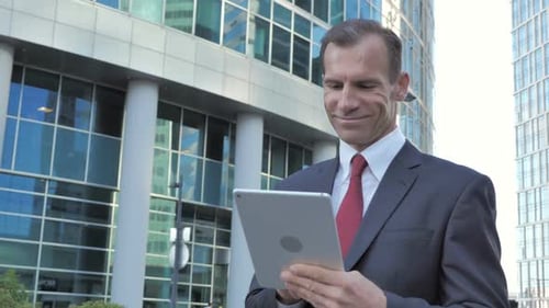 Businessman Using Tablet Outside Modern Office Building