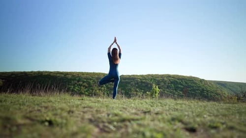 Frau praktiziert in Vriksasana Pose eines Baumes beim Yoga auf High Hill