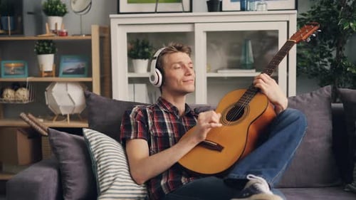 Relaxed Man Plays Guitar on Couch at Home