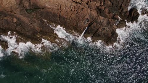 Ocean blue waves break on high cliff of a rocky mountain. Danger sea waves on a beach.
