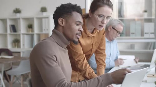 Coworkers Collaborating on Laptop in Office