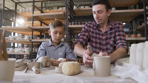 Boy and Man Making Pottery Together Indoors