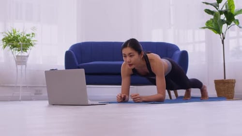 Woman Doing Plank Exercise Watching Laptop at Home