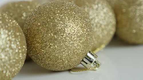 Sparkling Gold Christmas Ornaments on White Surface