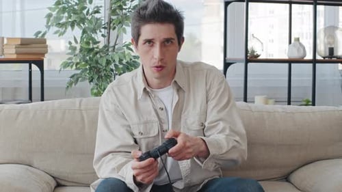 Focused Young Adult Gaming at Home on Couch