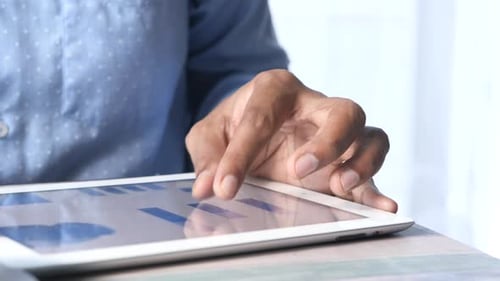 Young Man Analyzing Financial Data on Digital Tablet