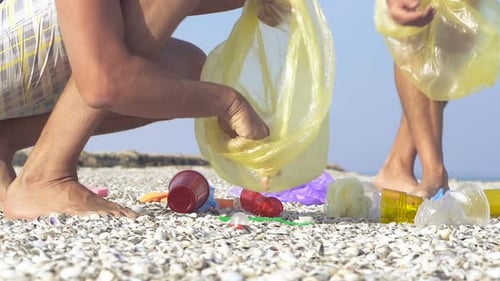 Dos hombres recogen basura de plástico en la playa. Cámara lenta