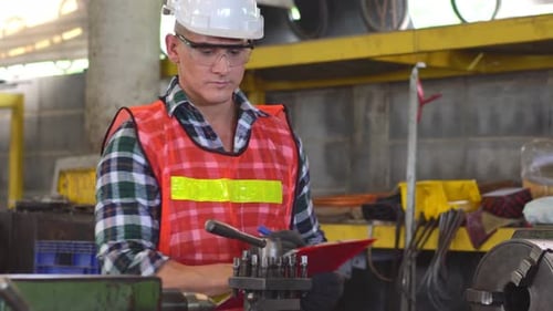 Engineer foreman writing on repair checklist inspecting on machine in the factory