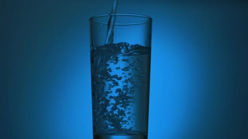 Transparent Glass On A Blue Background With Pouring Water
