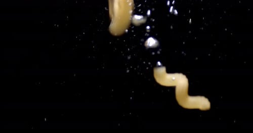 Cavatappi Dry Pasta Falls Under Water with Air Bubbles.