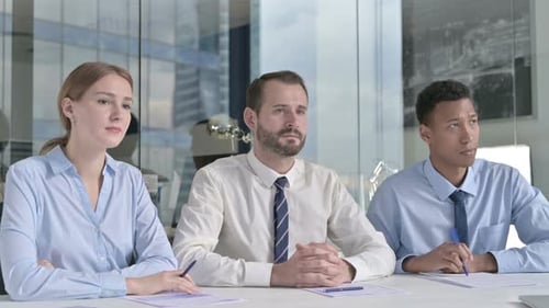Middle Aged Businessman Giving Introduction with Assistants on Office Table