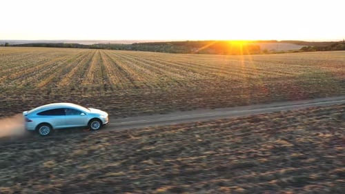 Aerial View of Electrical Car Moving Through Dusty Route. Drone Tracking Modern Vehicle Driving