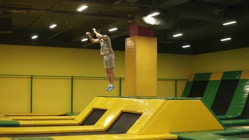 Young Man Performs Gymnastic Flips on Trampoline