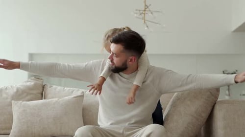 Father and Daughter Play Airplane on Sofa