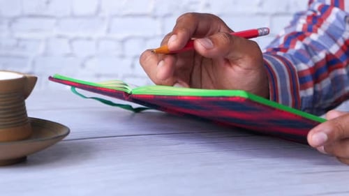 Close Up of Man Hand Writing on Notepad.