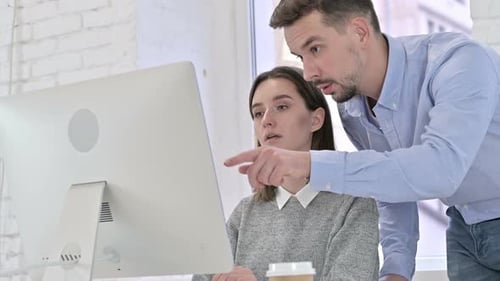 Man and Woman Collaborating at the Office Computer