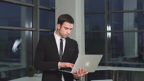 Portrait of Businessman in Office with Laptop Computer