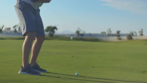 Man Swings Golf Club on Sunny Golf Course