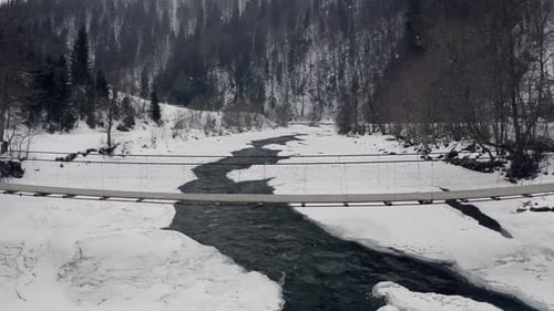 Old Wooden Bridge Over The Mountain River In Winter Forest