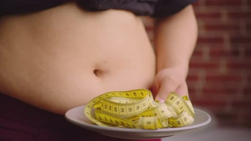 Person Displaying Abdomen with Measuring Tape on Plate