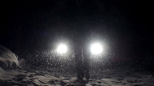 Car Lights Illuminate a Snowy Blizzard at Night
