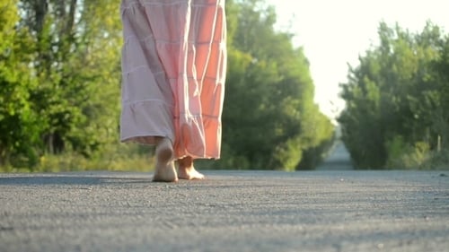 Menina em um vestido rosa andando na estrada