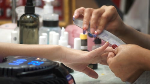 Manicurist Filing Nails With Colorful Design