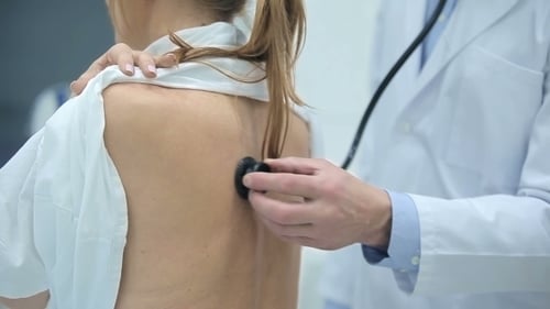 Doctor Listening to Woman's Back with Stethoscope