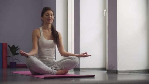 Woman Meditating on a Yoga Mat Indoors