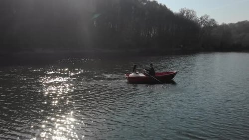 Aerial Shot of Brides Swim in a Red Boat. The Bright Sun Is Reflected in the Lake Creating a