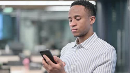 Young Adult Using Smartphone in Modern Office