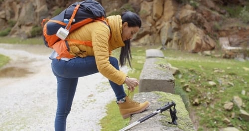 Woman Hiker Tying Boot Laces on Mountain Trail