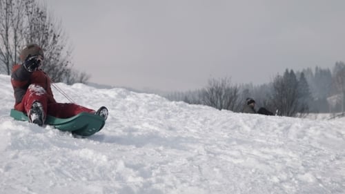 Der Junge klettert auf einem Schlitten auf einem Hügel