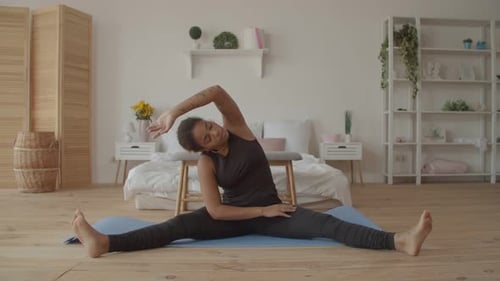 Young Woman Stretches in Bright Bedroom