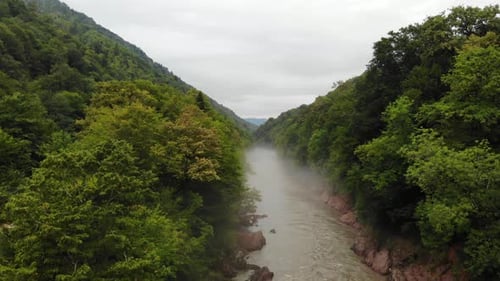 Flying over the mountain river with fog.