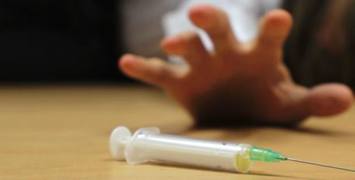 Viciado em drogas dopado estendendo a mão em direção à seringa