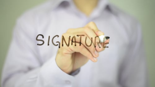 Hand Writes Signature with Marker on Clear Surface