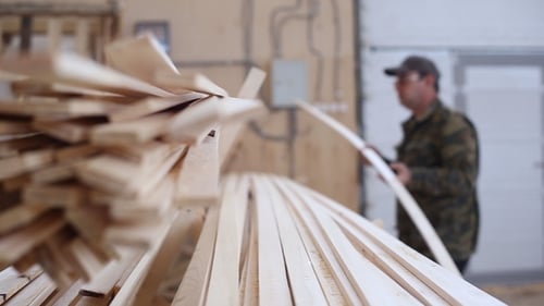 Man Inspecting Wood Planks in a Warehouse