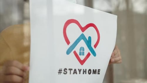 Person in Mask Holding Stay Home Sign